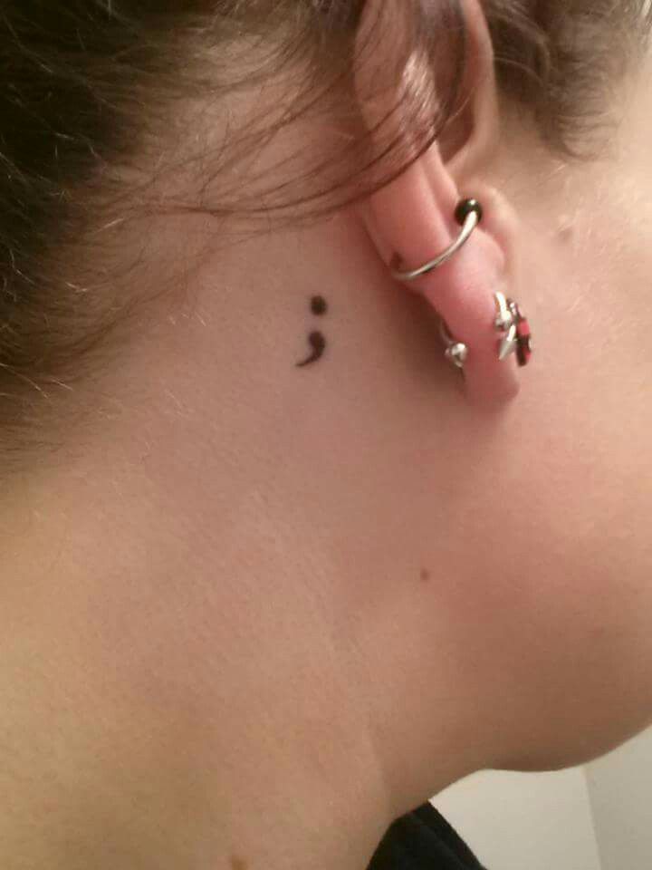 a woman's left ear has a small tattoo on it