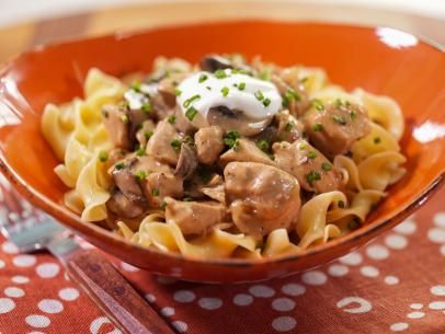 a bowl filled with pasta and meat covered in sour cream on top of a polka dot table cloth