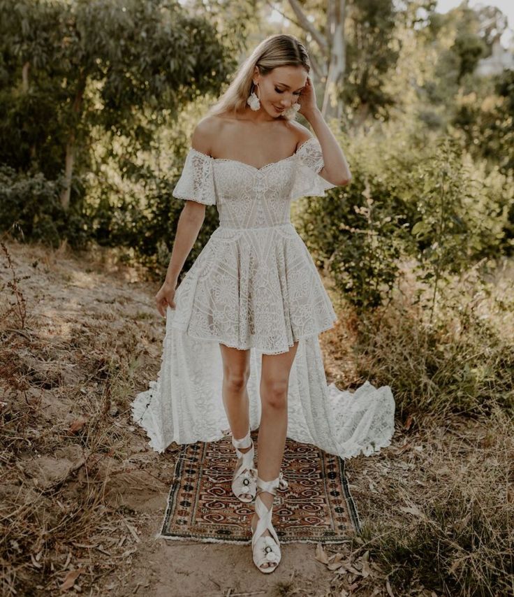 a woman in a white dress is standing on a rug with her hands behind her head