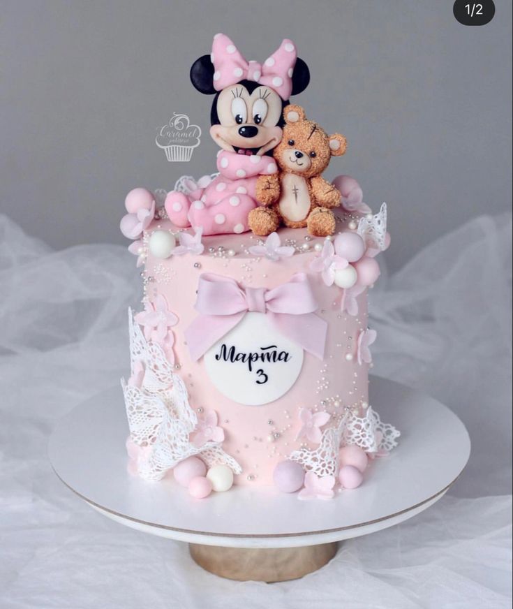 there is a pink cake with minnie and mickey mouse on top, decorated with teddy bears