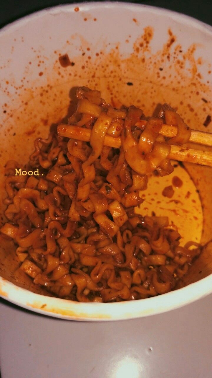 a white bowl filled with noodles and chopsticks on top of a stovetop