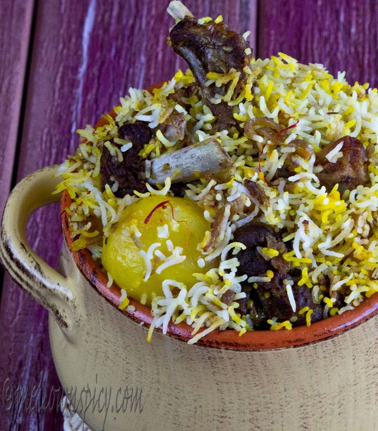 a bowl filled with rice and vegetables on top of a wooden table