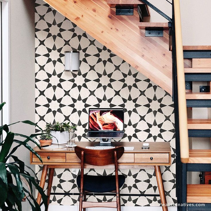 a desk with a laptop on it under a stair case next to a potted plant