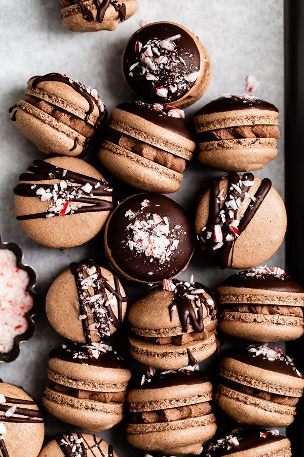 chocolate macaroons with sprinkles and candies are arranged on a table