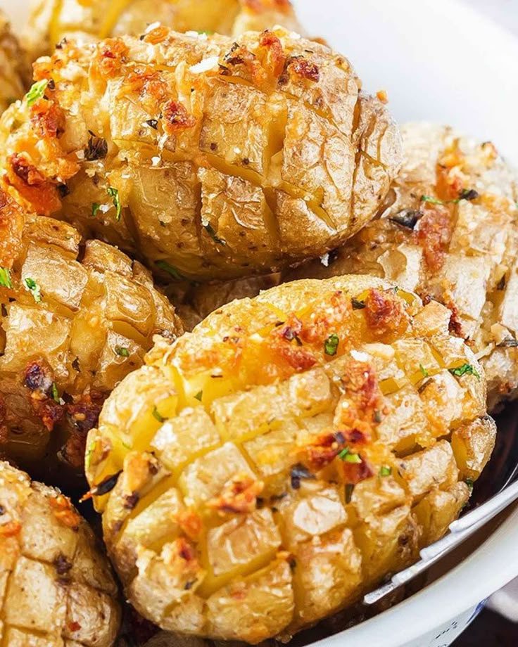 a bowl filled with potatoes covered in seasoning and garnished on the side