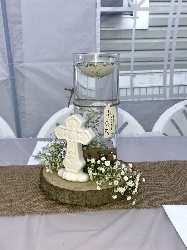 a table topped with a vase filled with flowers and a cross on top of it