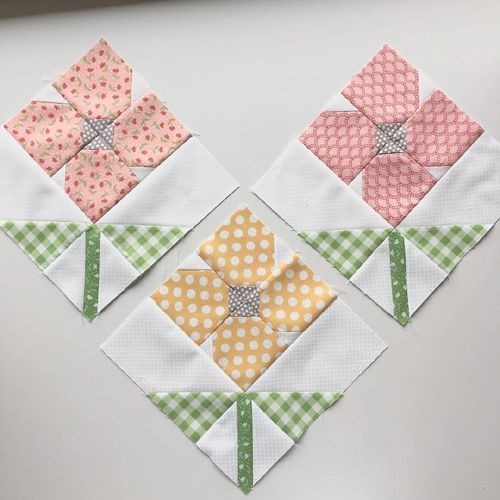 three small quilted squares with flowers on them, one in the shape of a heart