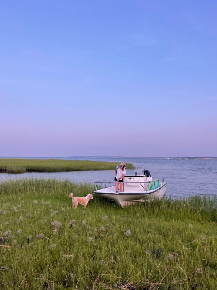 a man standing next to a boat on top of a lush green field