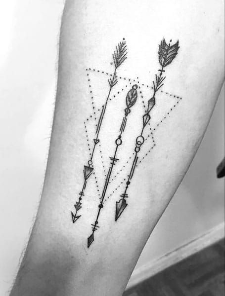 an arrow tattoo on the left leg with arrows and dots in black ink above it