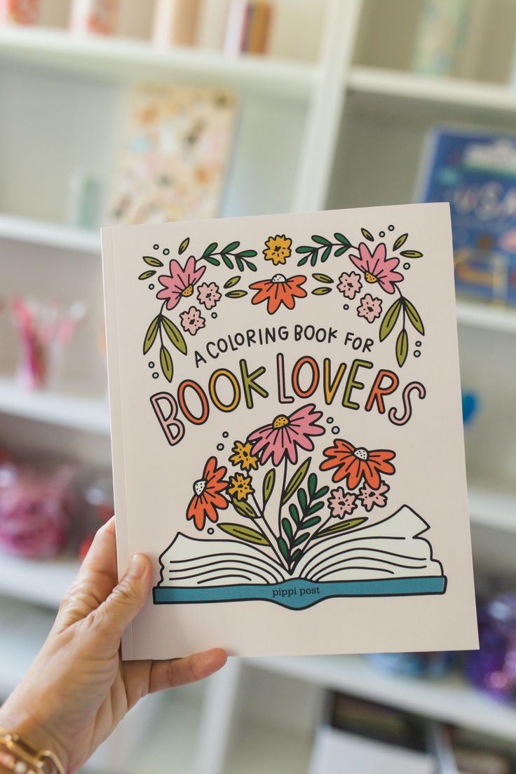 a person holding up a book with flowers on it