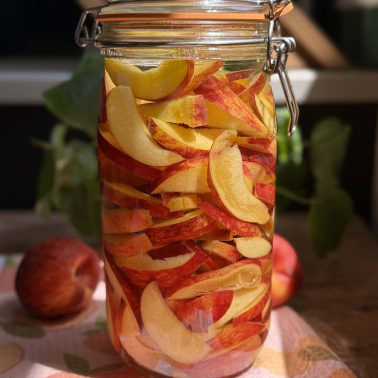 a glass jar filled with sliced apples on top of a table