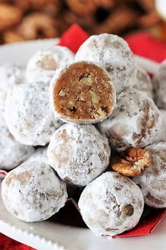 a white plate topped with chocolate covered donuts and walnuts next to a pile of cookies