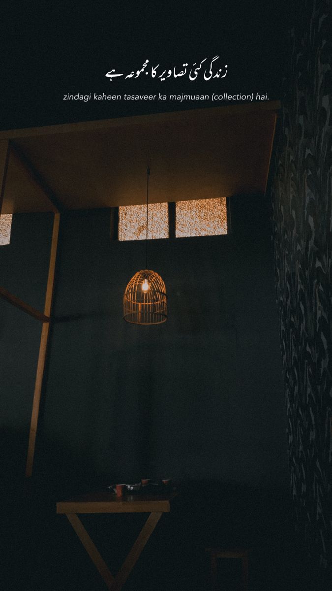 a dark room with a lamp hanging from it's ceiling and the words in arabic on the wall