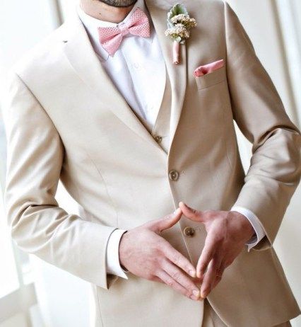 a man in a tan suit and pink bow tie