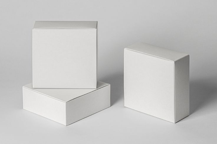 two white boxes sitting next to each other on top of a gray surface with one box open and the other closed