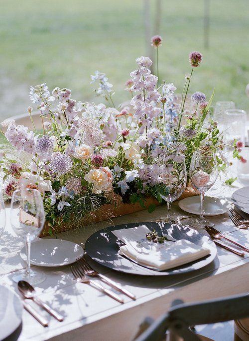 the table is set with plates, silverware and floral centerpieces on it