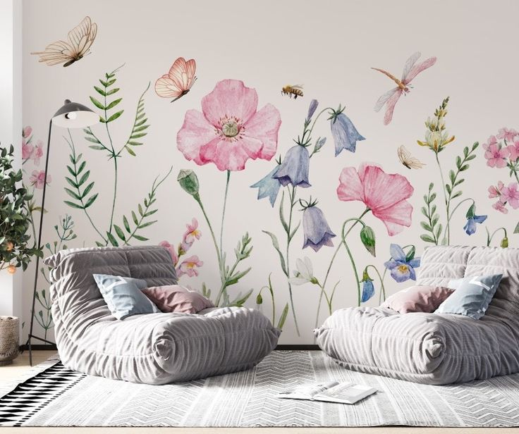 two couches in front of a wall with flowers and butterflies painted on the walls