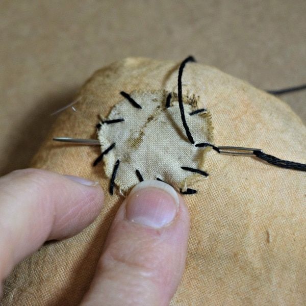 a person is stitching something on top of a piece of fabric with pins in it