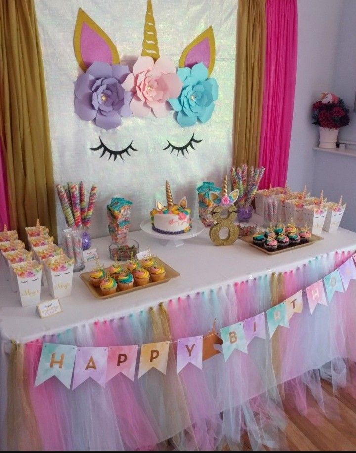 a table topped with lots of cupcakes and cake next to a unicorn head