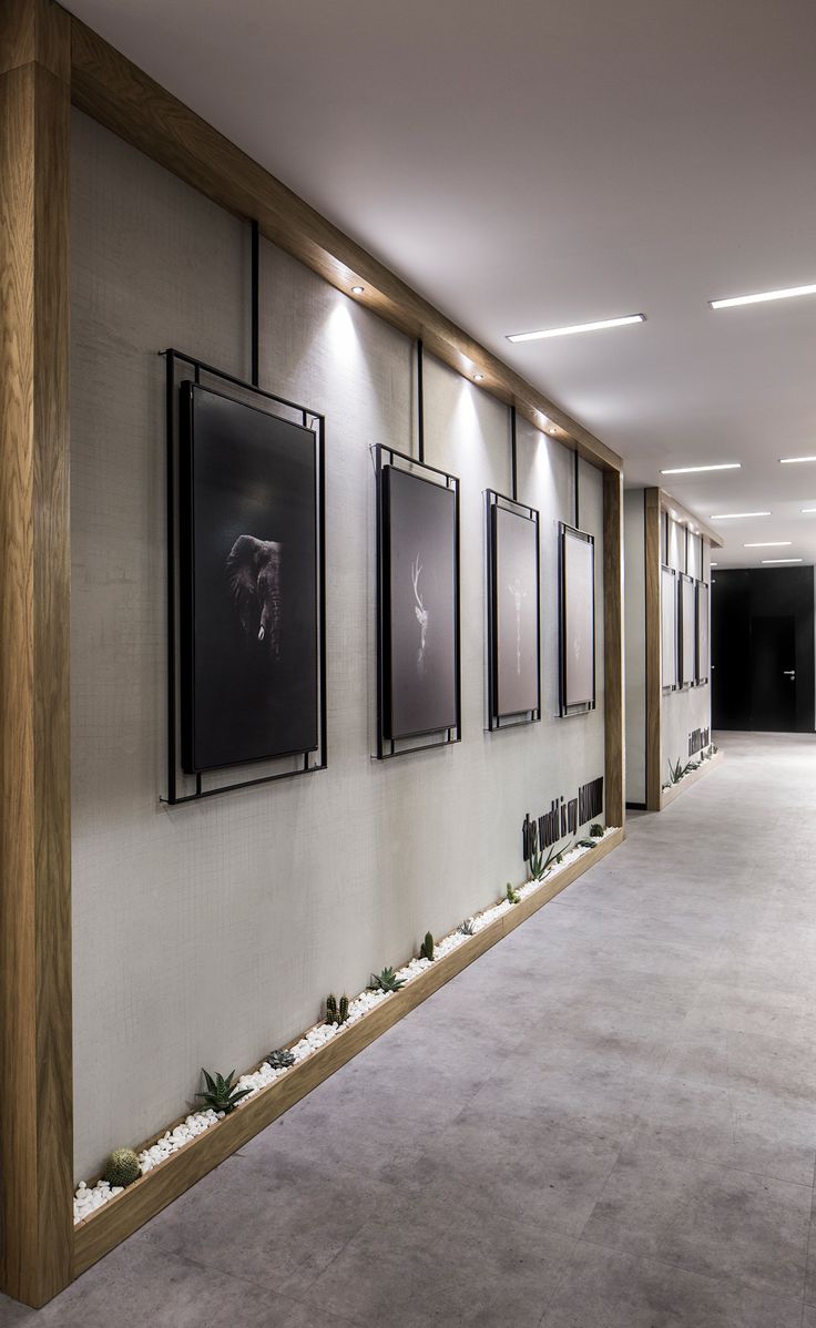 an empty hallway with pictures on the wall and plants growing in the planter boxes