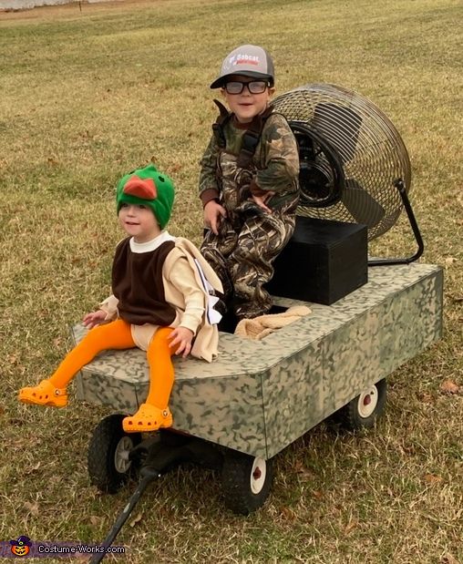 two young boys sitting on top of a toy cart with an air mover in the back