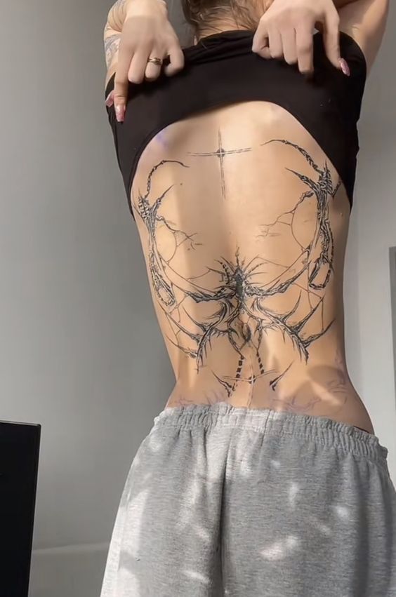 the back of a woman's body with tattoos on her stomach and lower back