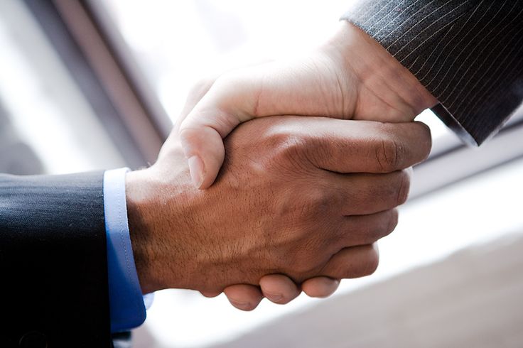 two men shaking hands in front of a window