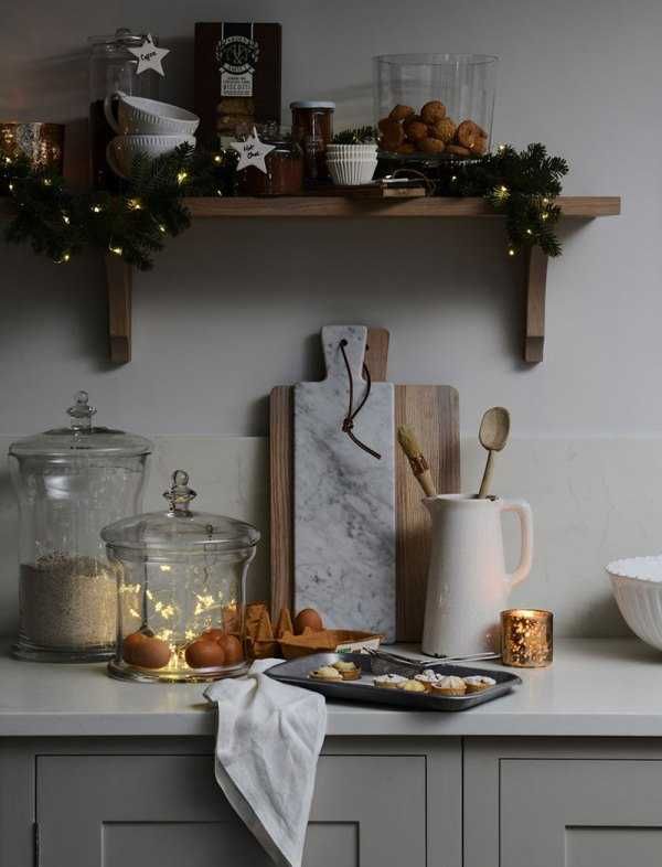 a kitchen counter topped with lots of food next to a shelf filled with christmas decorations