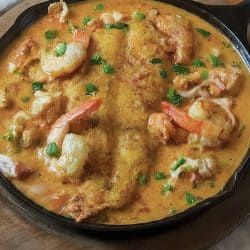 a skillet filled with shrimp and grits on top of a wooden table