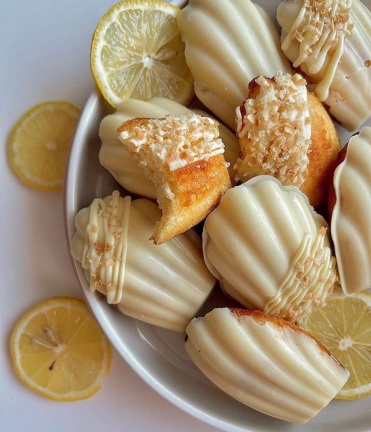 a white plate topped with lemon filled pastries next to slices of lemon wedges