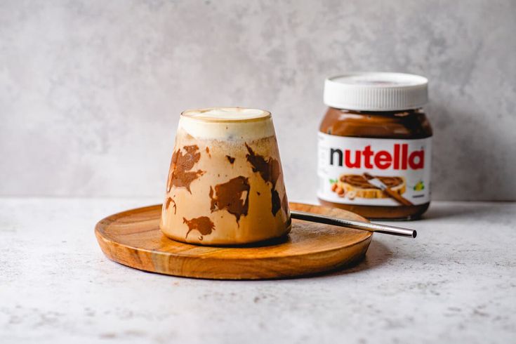 a nutella jar sitting on top of a wooden plate next to a jar of peanut butter