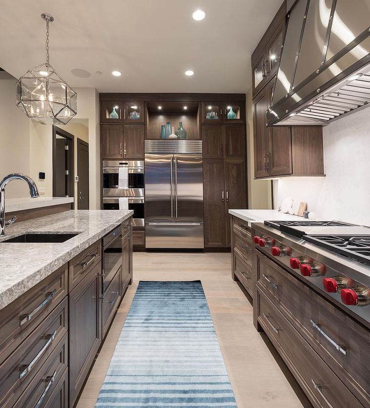 an image of a kitchen with brown cabinets and blue rugs on the counter top