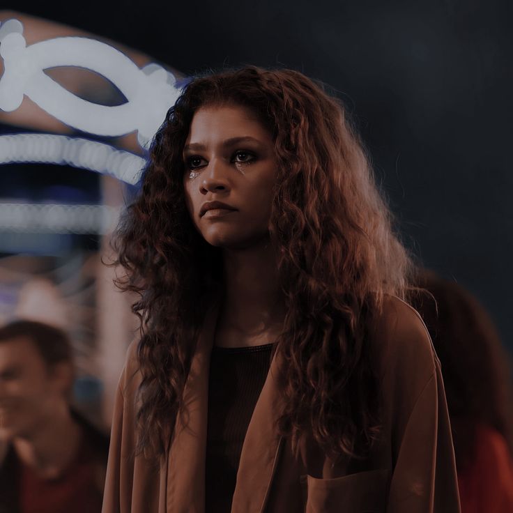 a woman with long curly hair standing in front of a sign that says o2