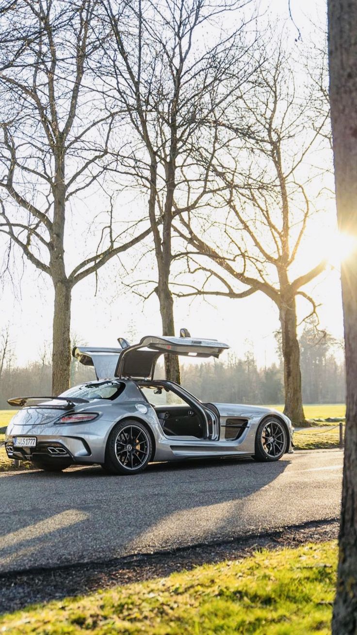 a silver sports car is parked on the side of the road with its doors open