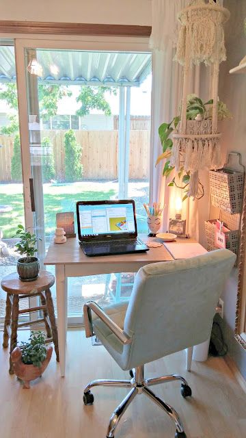 a laptop computer sitting on top of a wooden desk in front of a large window