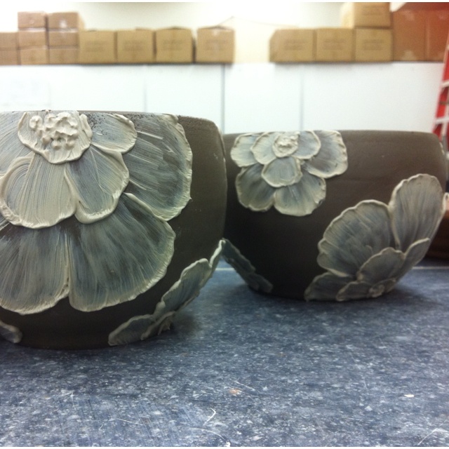 two vases sitting on top of a counter next to each other with flowers painted on them