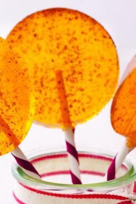 two orange lollipops in a glass jar with candy sticks sticking out of them