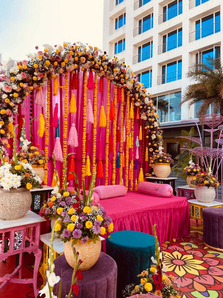 an outdoor ceremony with bright colors and flowers on the stage, surrounded by tall buildings