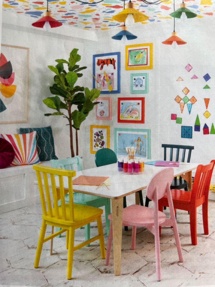 a room with colorful chairs and paintings on the wall, including a white dining table