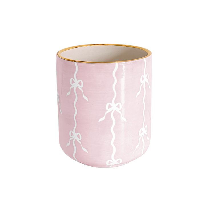 a pink and white vase with bows on the inside, sitting against a white background