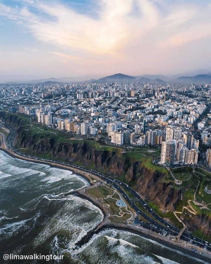 an aerial view of a large city next to the ocean with waves crashing on it