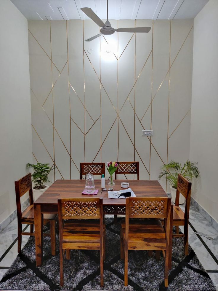 a wooden table with four chairs and a fan in the corner next to it on a rug