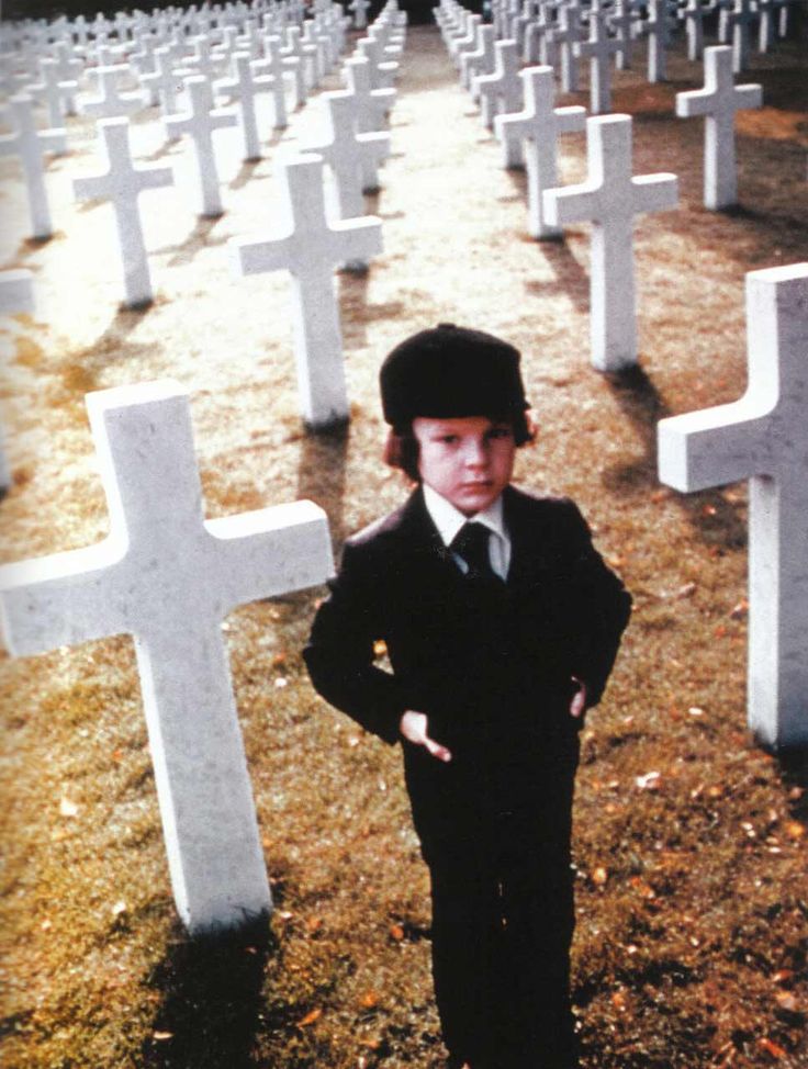 a young boy standing in front of rows of crosses