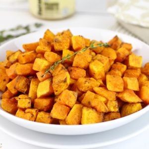 a white bowl filled with sweet potatoes on top of a table