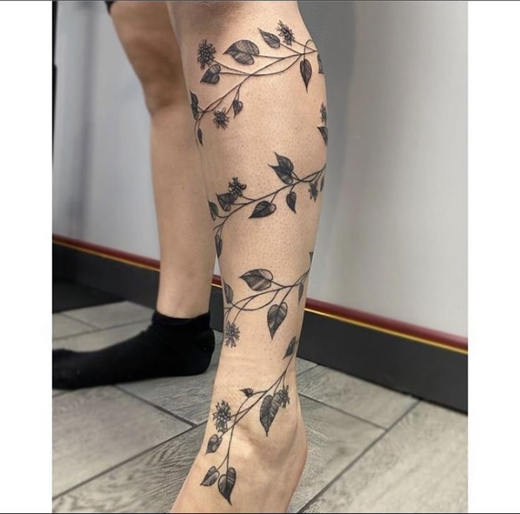 a woman's legs with tattoos on them and flowers all over the leg area