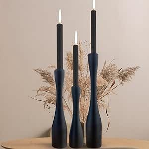 three black candles sitting on top of a wooden table