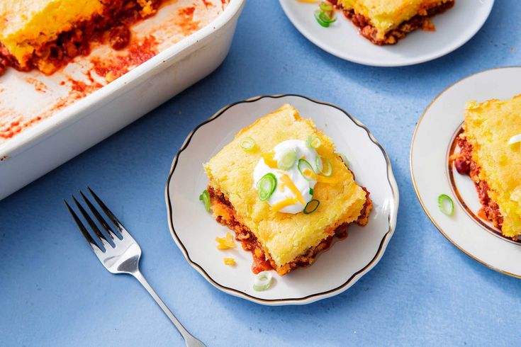 two plates with lasagna casserole on them next to a baking dish