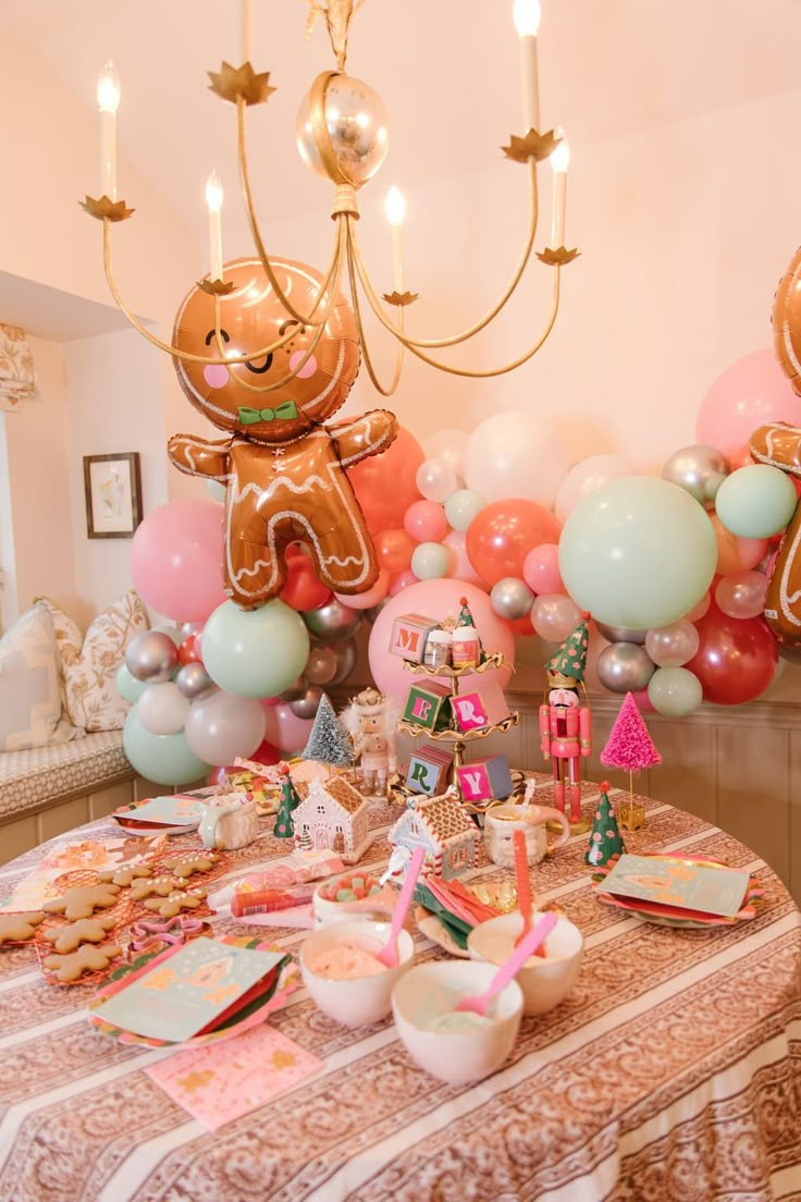 a table topped with lots of food and balloons in the shape of gingerbread man