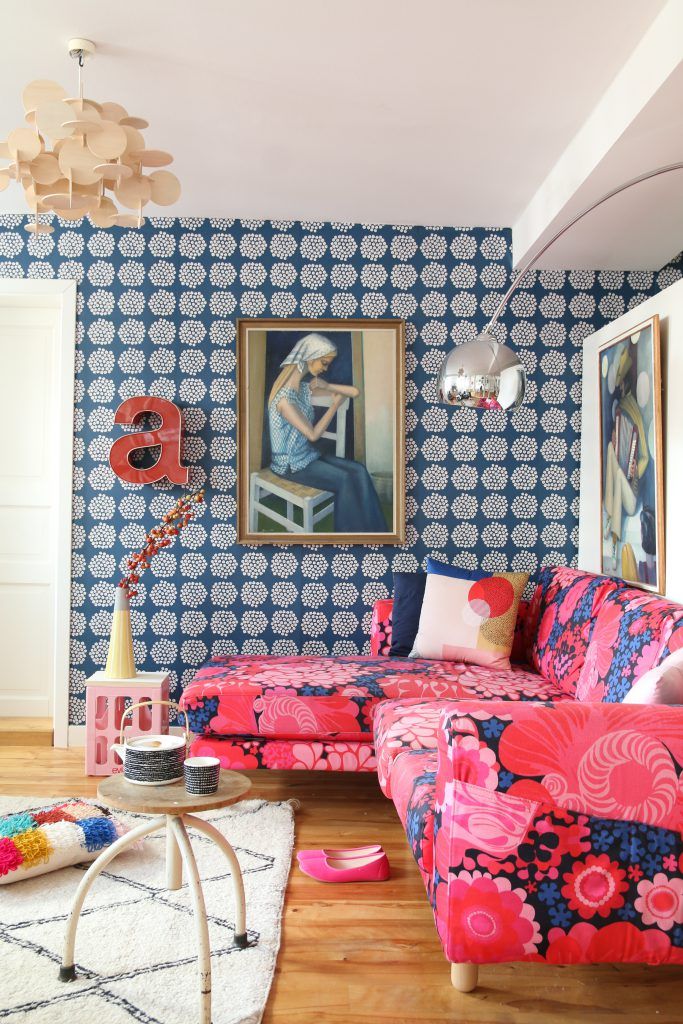 a living room with blue and pink wallpaper, white rugs and colorful couches