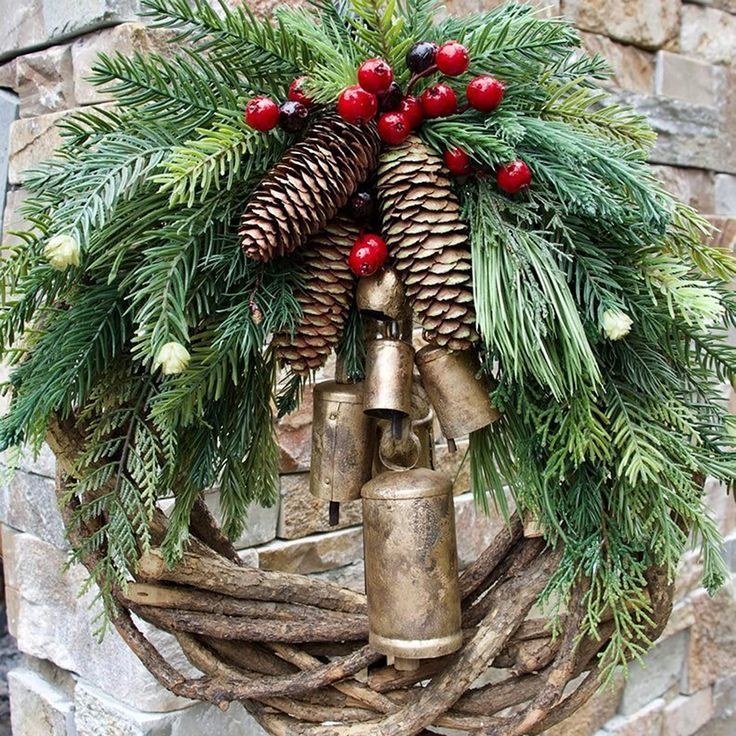 a christmas wreath with pine cones and red berries hanging from it's centerpiece